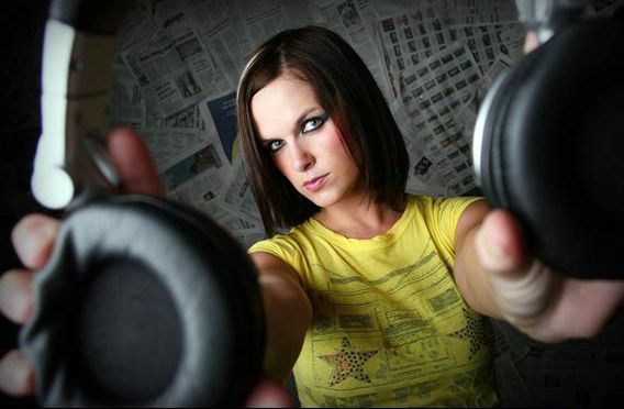 Kelly holding headphones out toward the camera